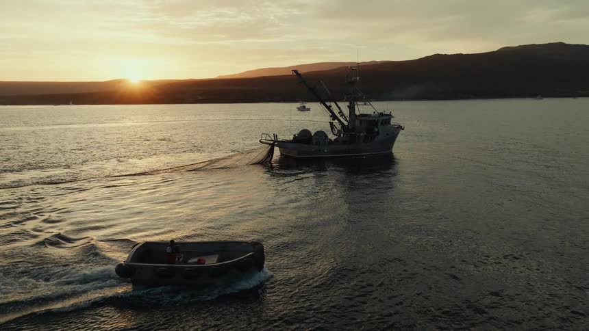 Fishing boats on a calm sea with mountains in the background