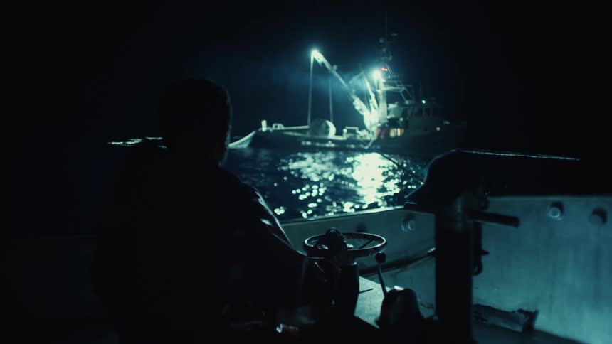 A fisherman is working on the boat at night