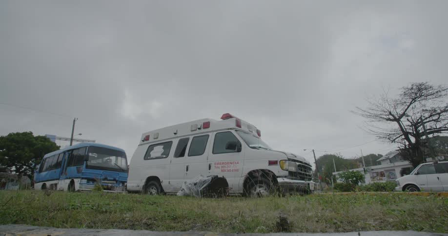 Emergency vehicle parked in front of bus on street on cloudy day
