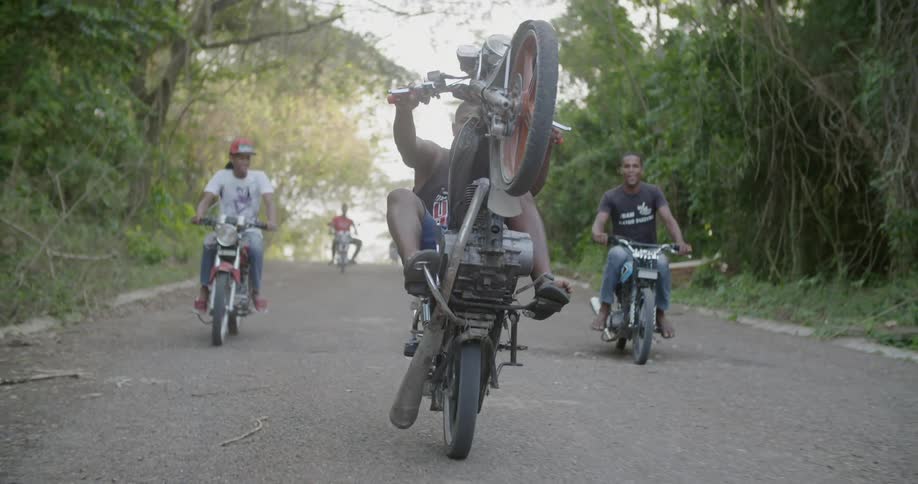 A man performs a wheelie on a motorcycle