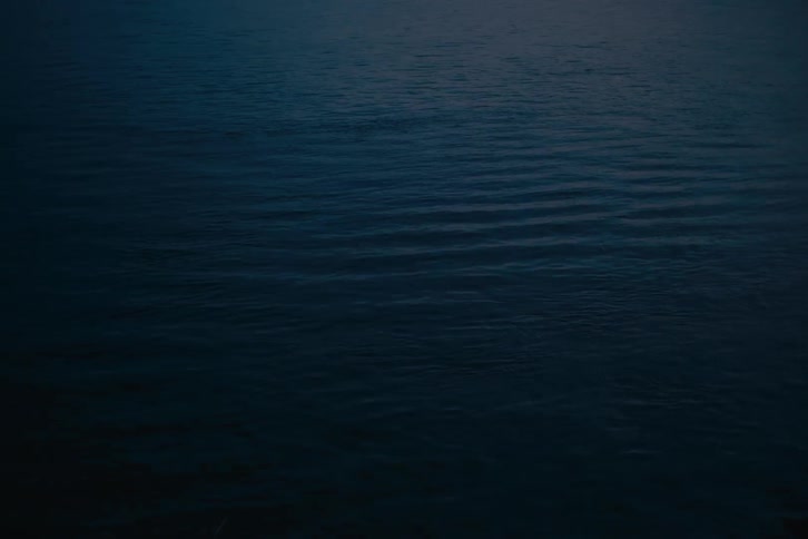 Dark calm water ripples gently across the surface in the fading light