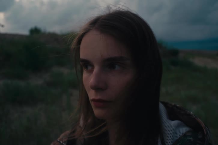 Young woman with a pensive expression her face softly illuminated against a dark outoffocus background