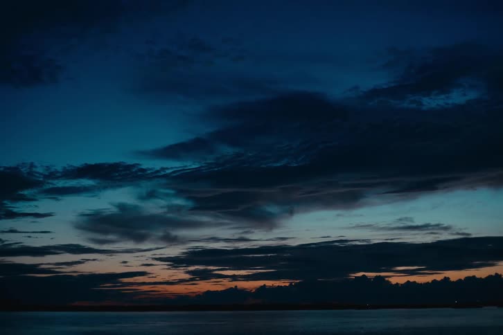 Dark blue sky with dramatic clouds at dusk over the sea