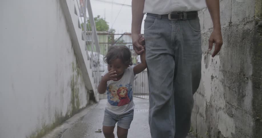 Man holding the hand of toddler girl and walking