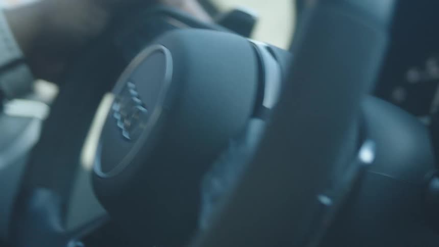 A closeup shows hands gripping the steering wheel of an audi vehicle