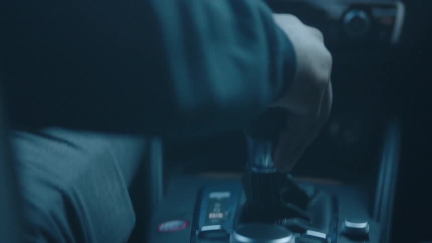 Hand grips the gear shift inside a moving car