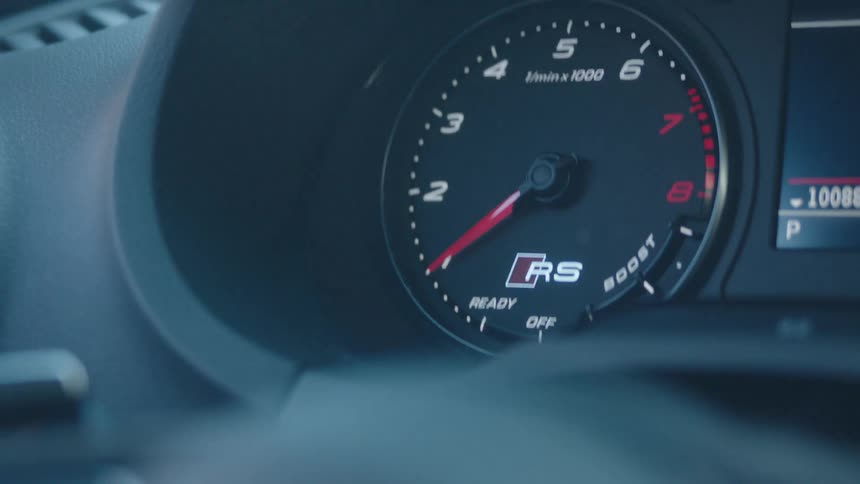 A close up shot focuses on the rpm gauge of a car where the needle fluctuates slightly indicating the engine is running