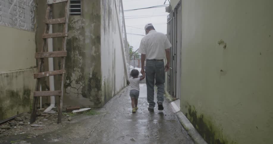 A man walks a young child down an alley