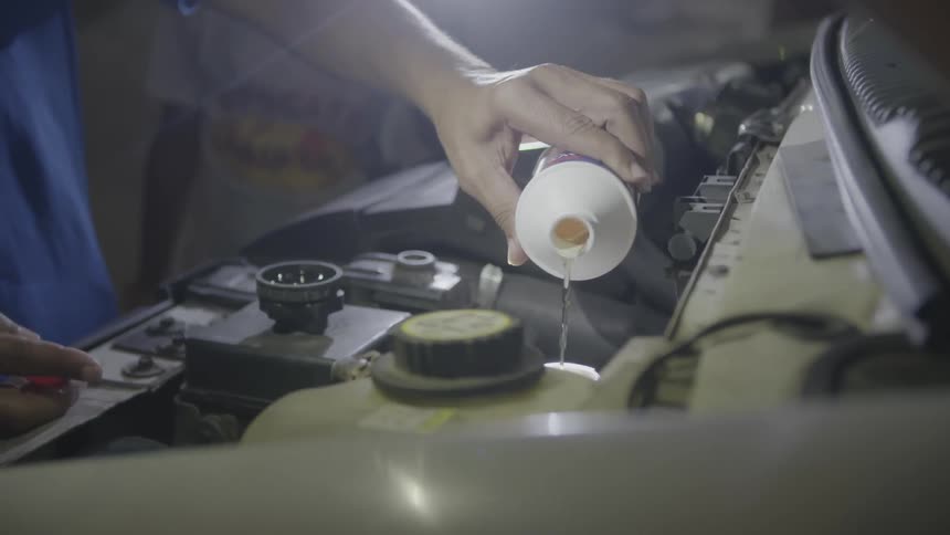 A fluid is poured under a car hood