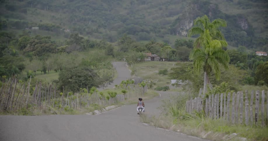 Two people ride a motorcycle on a rural road