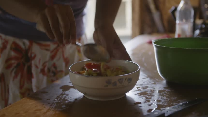 A woman stirs food in a bowl