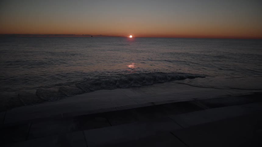 Gentle waves reach the shore at sunrise over the ocean