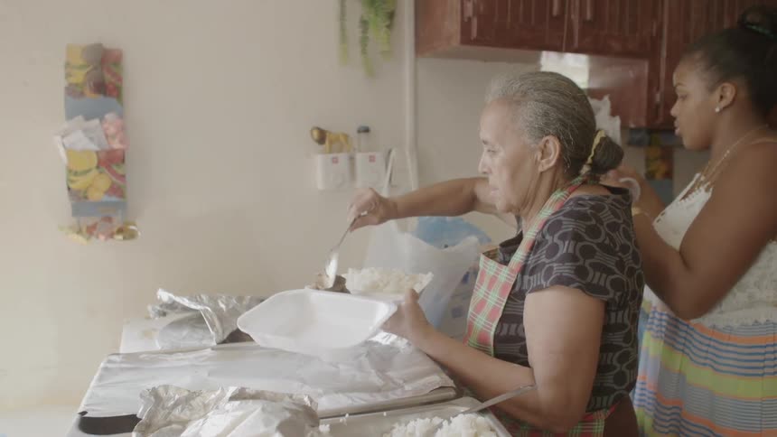 Two women serve food in a kitchen