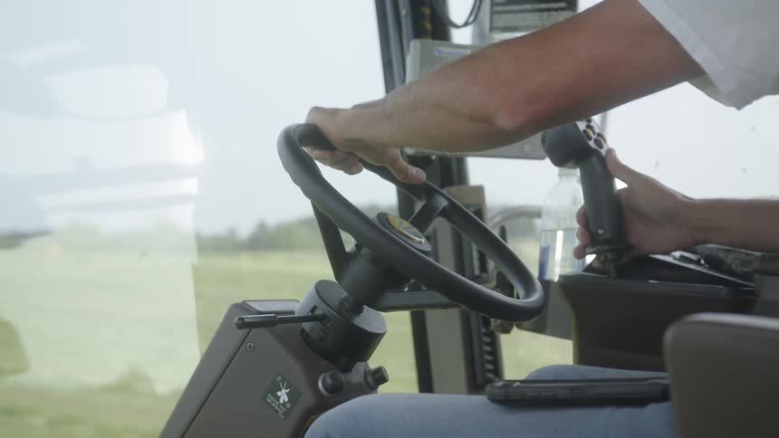 A person operates a tractor in a agricultural field at midday