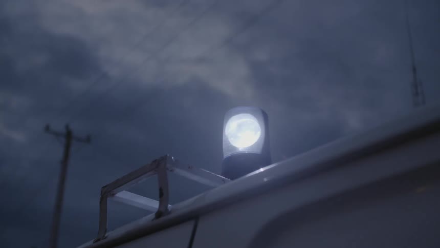 An ambulance light spins and illuminates the night