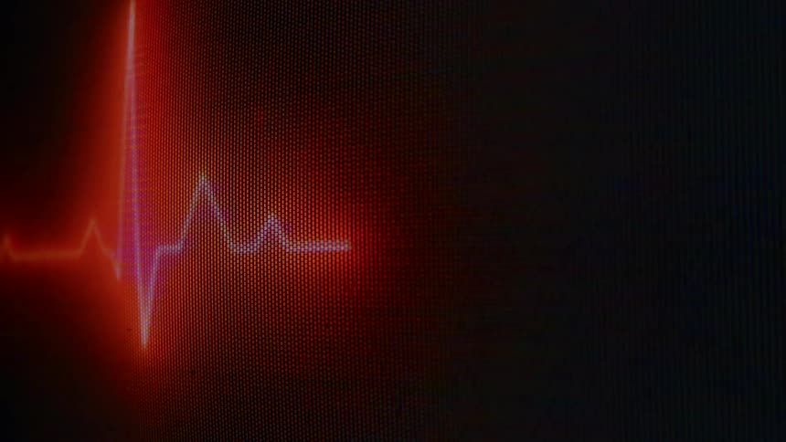 A bright orange and red pulsating heart rate monitor line moves across a dark pixelated screen indicating a fluctuating heart rhythm