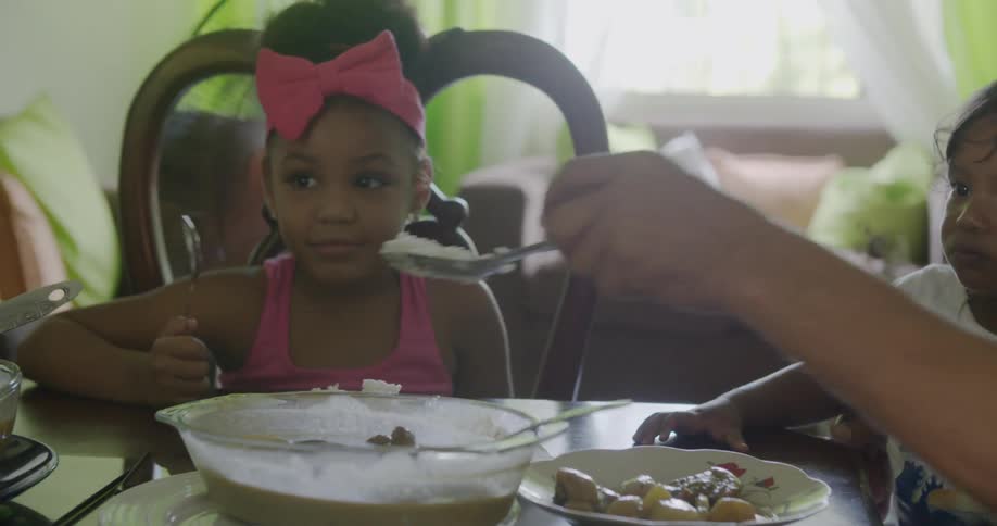 Person scooping rice onto child's plate at dinner table