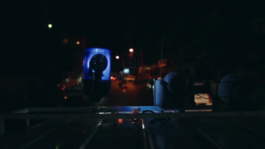 A blue light spins on top of a white vehicle