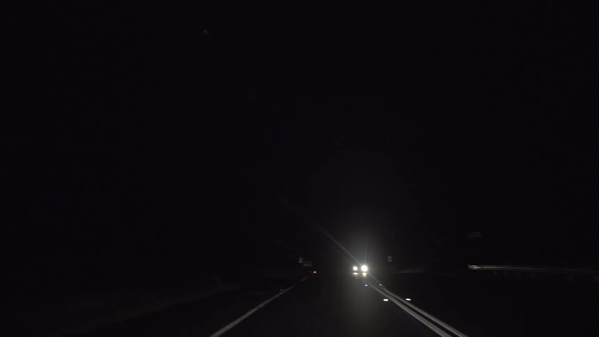 Headlights in the distance of a road on a dark night