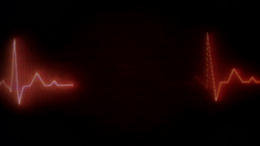A glowing red ekg line pulses on a black screen resembling a heartbeat monitor