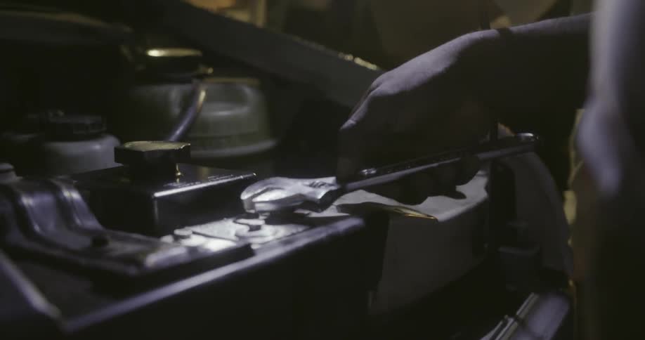 A man uses a wrench under the hood of a vehicle