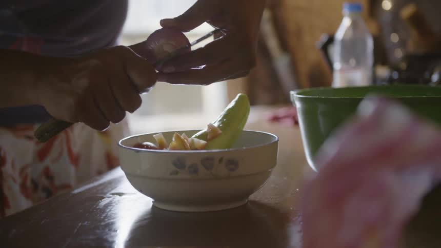Woman chopping up fruits into bowl in kitchen