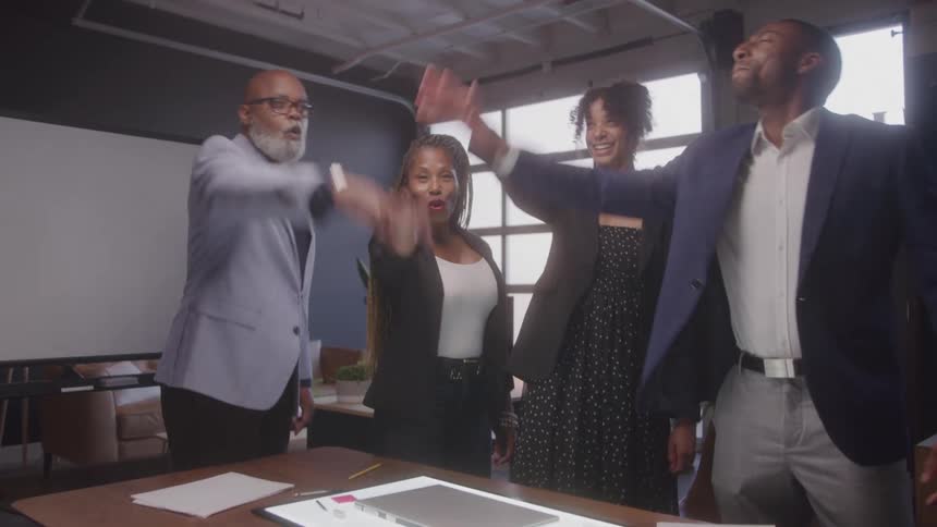 Coworkers huddle and cheer in the office