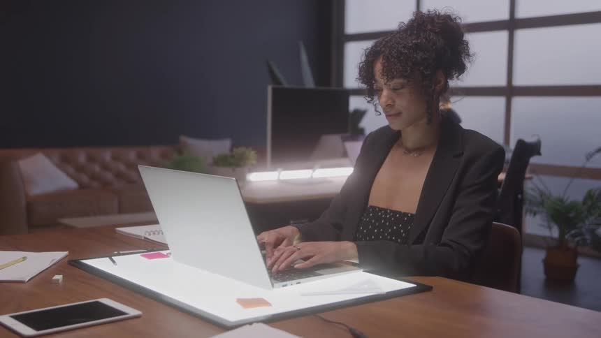 The woman in the office is typing on her laptop