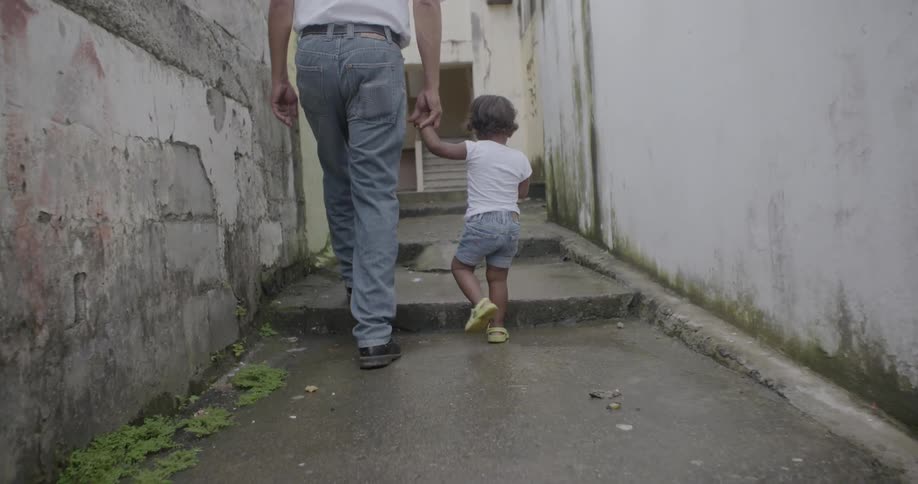 A man walks a young child down an alley