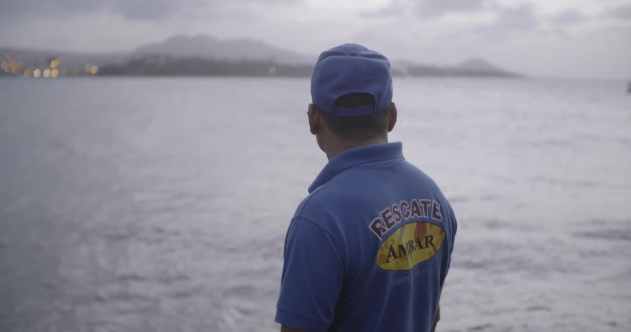Man standing a looking out at ocean water on cloudy day