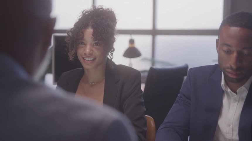 Three people sitting at a table in a business meeting