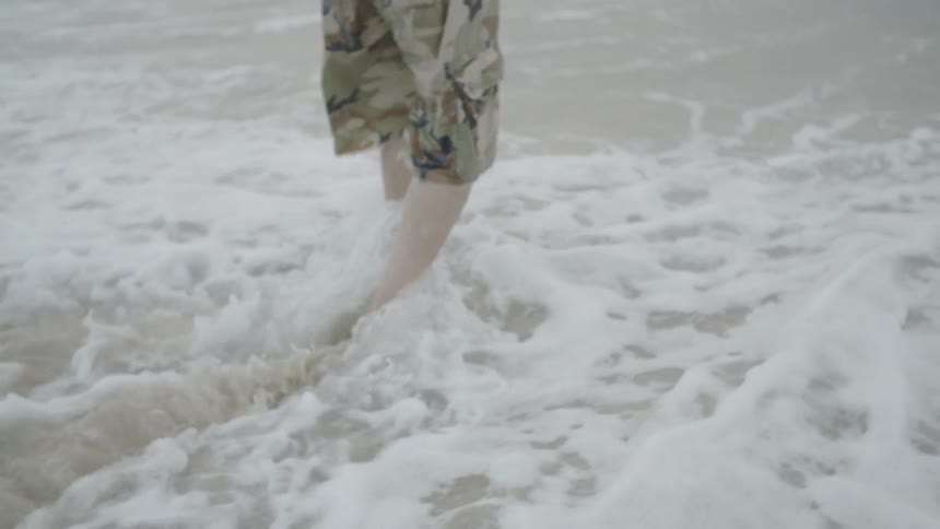 A person in shorts walks into the ocean