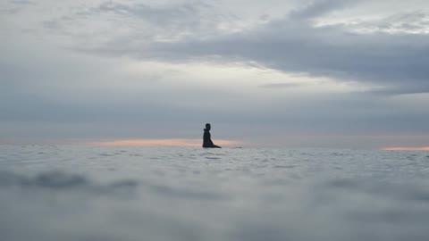 Person sitting on surfboard in isolated ocean