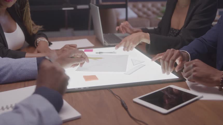 Group of people interacting with a tablet on a table in an office meeting