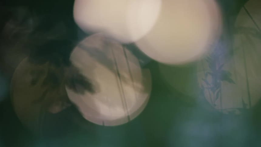 A blurry abstract view of a dark background with several large circular shapes of light that fade in and out of focus