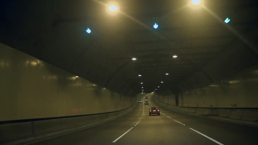 Vehicles travelling through a tunnel as lights glow overhead
