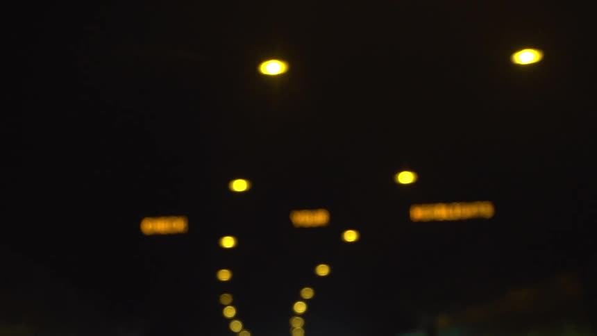 A strip of yellow lights and flashing signs on the ceiling of a tunnel