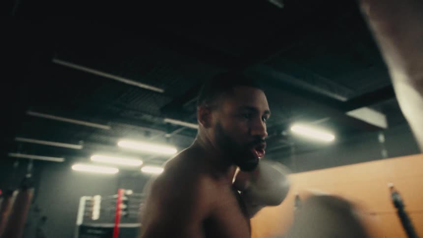 Close up of a young black man training punches with a punching bag in a boxing training room