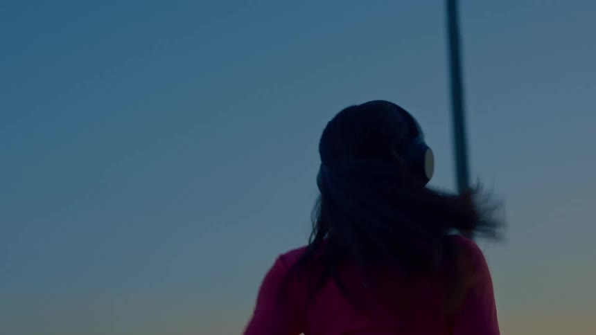 Woman jogging at sunset with headphones in a treelined area