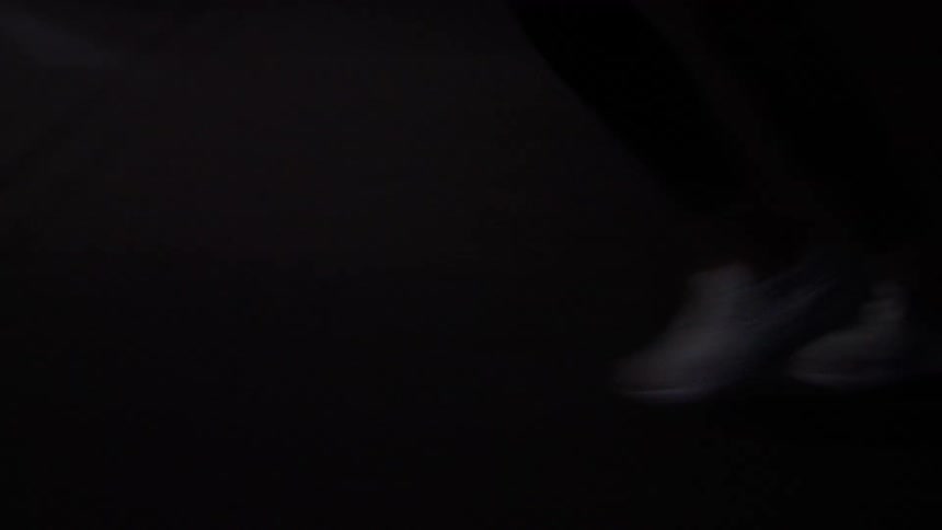 Close up of a young womans legs as she jogs across a street outdoors at night