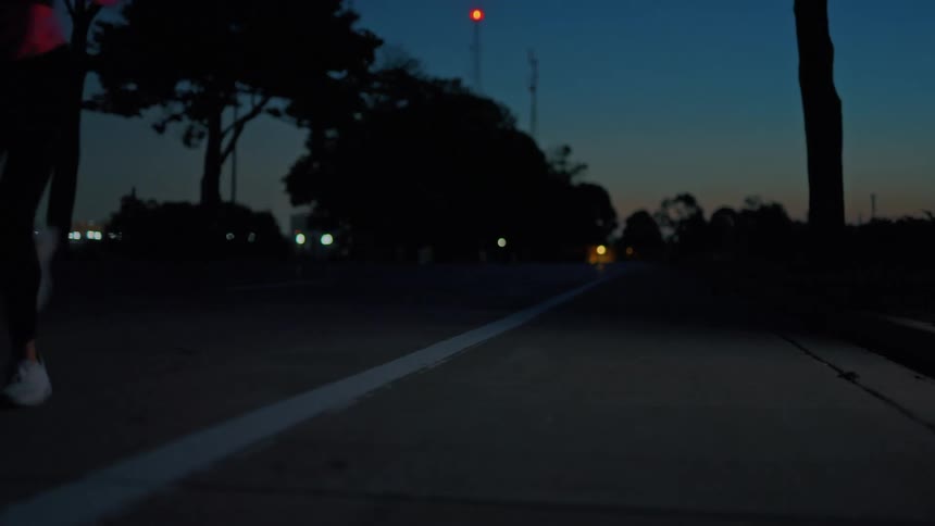 A young black woman jogs on an empty street outdoors in the evening