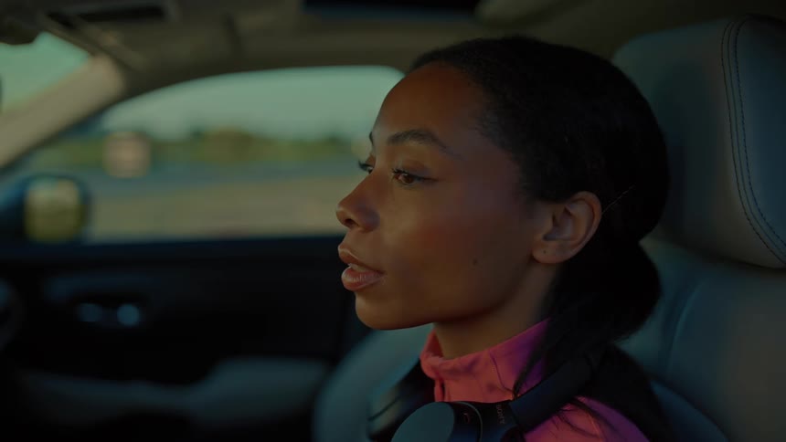 A woman wearing headphones sits in a car