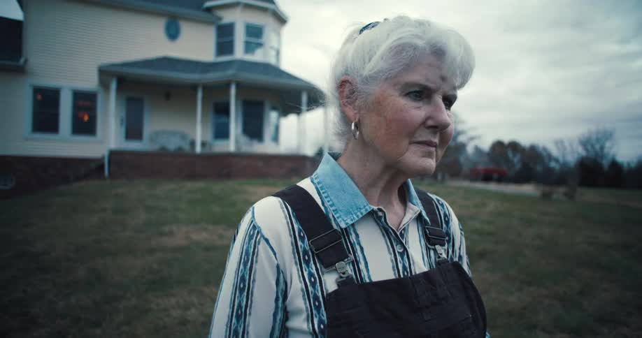 An older woman stands outside in a backyard
