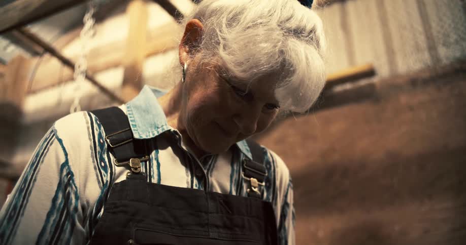 The woman is standing in the barn
