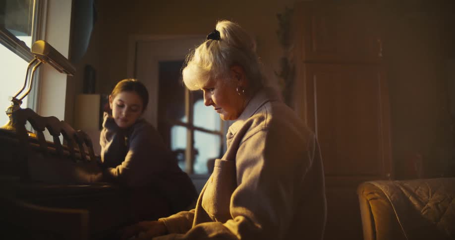 A teenager listens to a woman play the piano