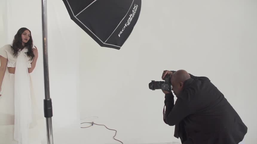 A man photographing a woman wearing a white dress