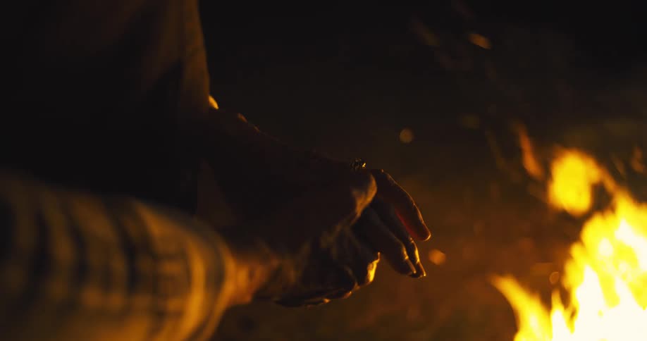 Elderly womans face illuminated by the warm light of the fire in the darkness