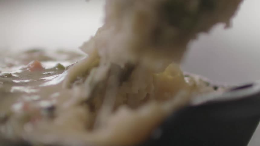 A casserole is scooped from a pan