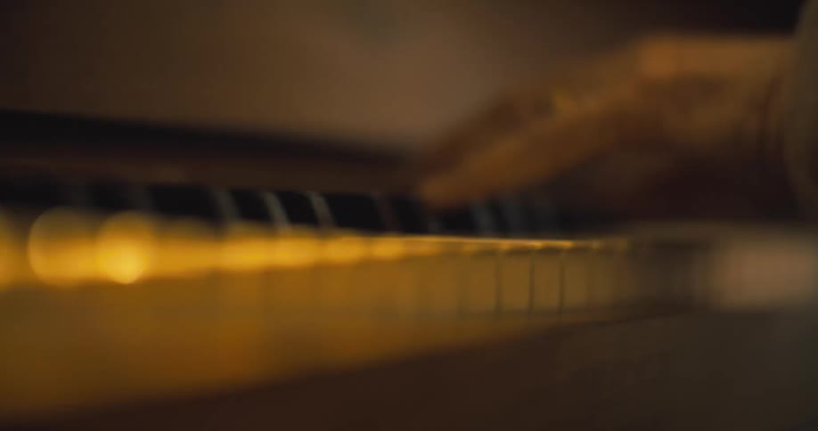 Elderly female pianist plays a piano while wearing a coat