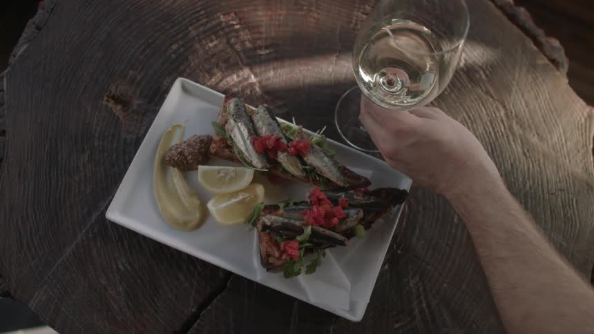 A person places a glass of wine next to a plate of food